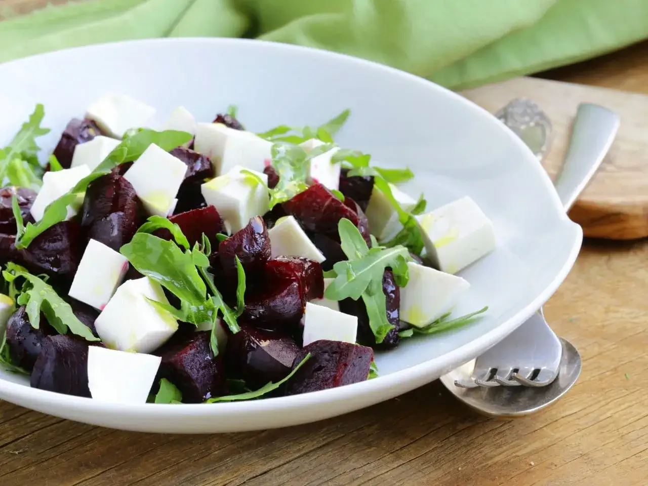 Ensalada de remolacha con cubos de queso blanco y rúcula, aderezada con aceite de oliva.