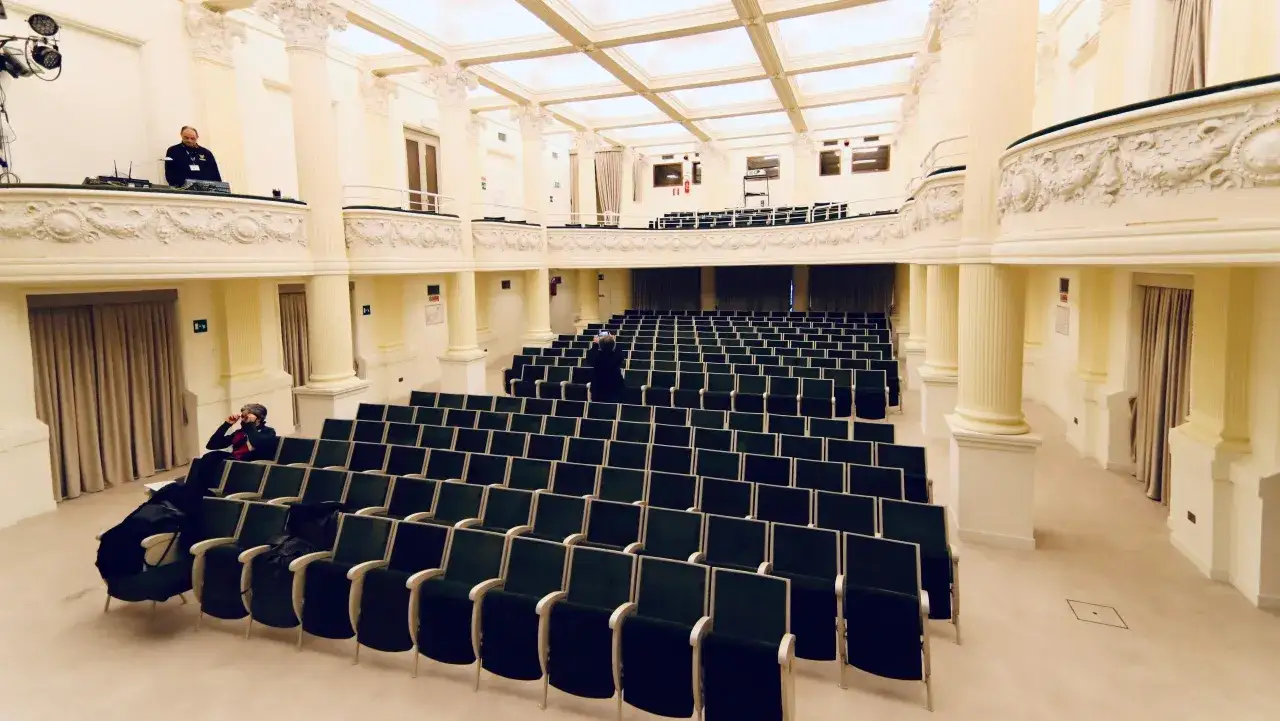 Sala vuota con file di sedie verdi, pronta per un evento da blockbuster.