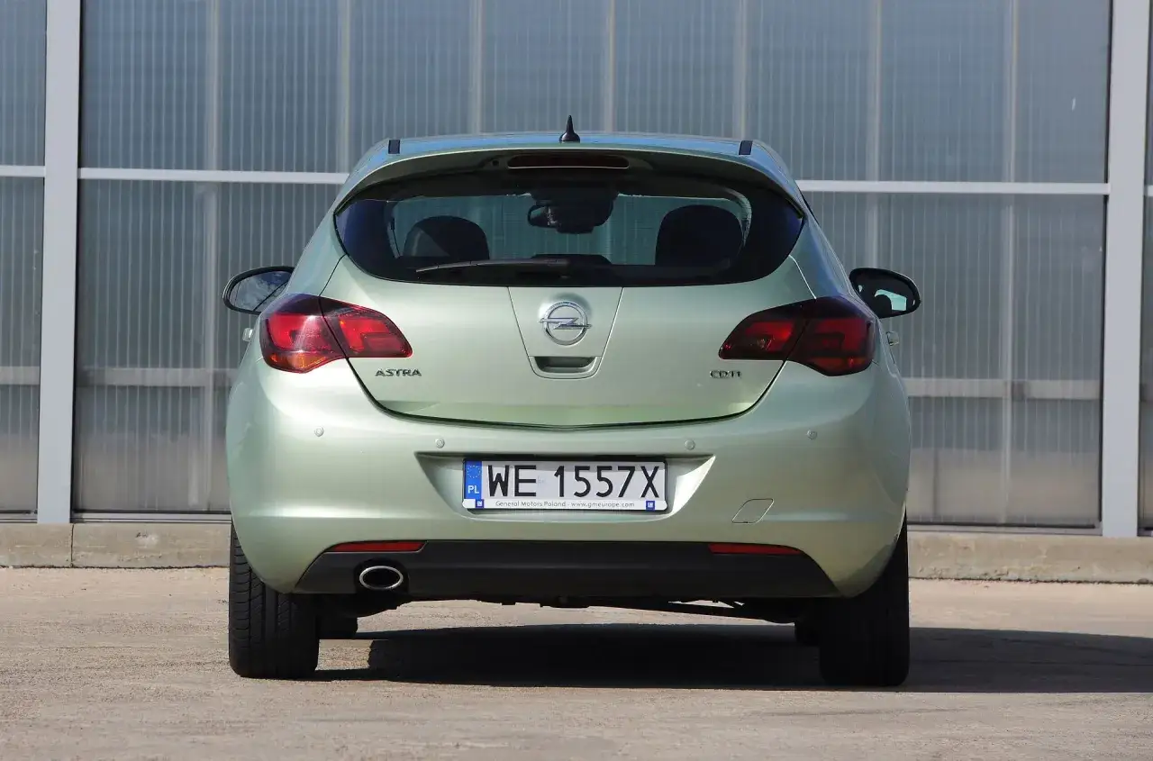 Tylna część zielonego Opla Astry J hatchback z widocznym logo, światłami i tablicą rejestracyjną WE 1557X.