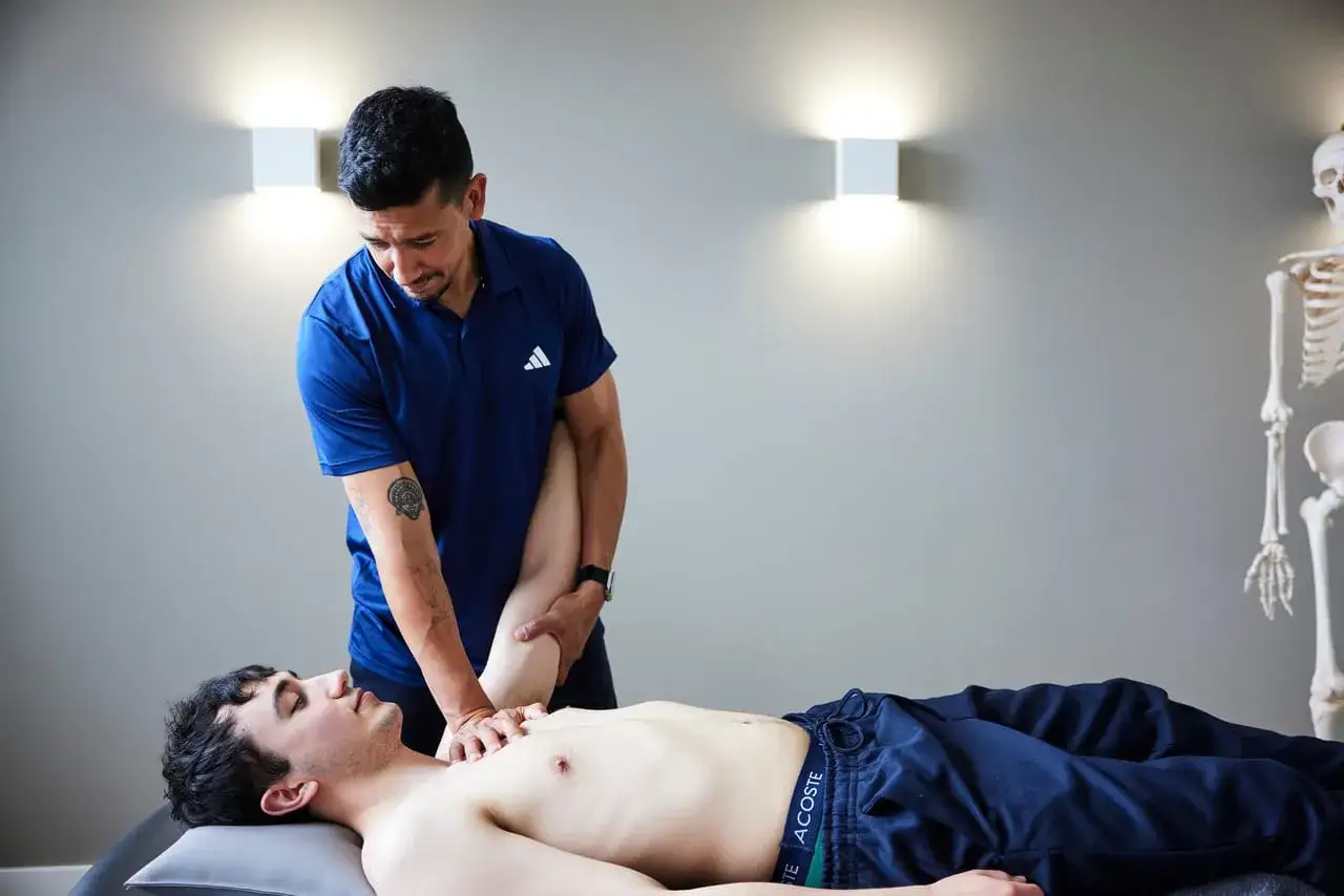 Osteopath behandelt einen Patienten mit Frozen Shoulder. Sanfte Hände mobilisieren den Arm für mehr Beweglichkeit.