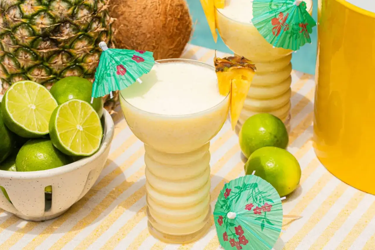 Tropikalne drinki z ananasem i limonką, ozdobione papierowymi parasolkami. Idealne na letnie przyjęcie.