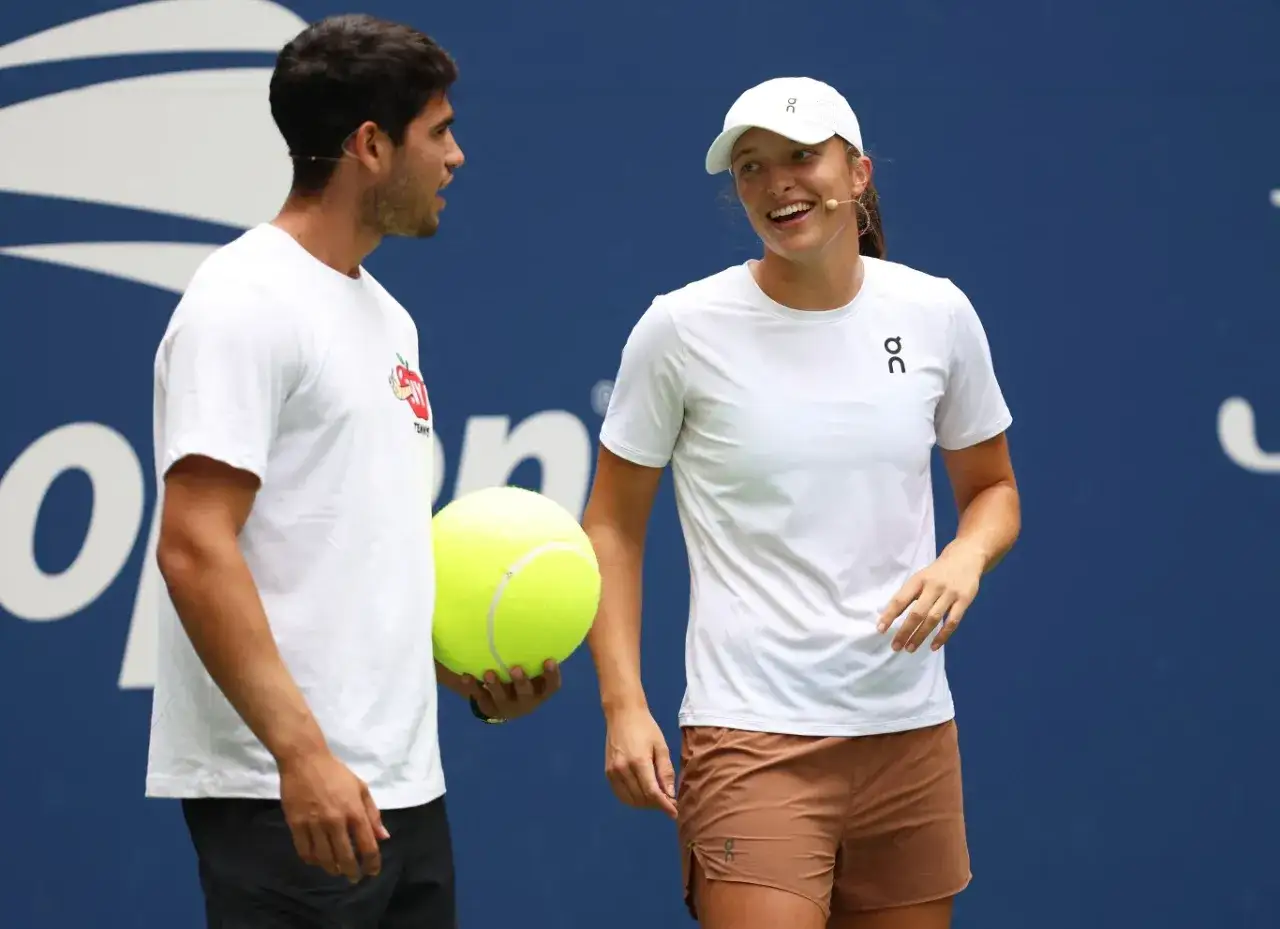 Carlos Alcaraz i Iga Świątek rozmawiają podczas Roland Garros 2024. Carlos trzyma wielką piłkę tenisową.