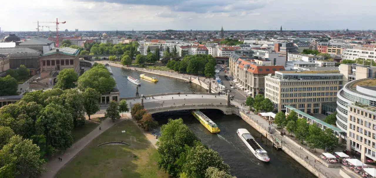 Blick auf die Spree in Berlin mit Schiffen, Brücken und Gebäuden.