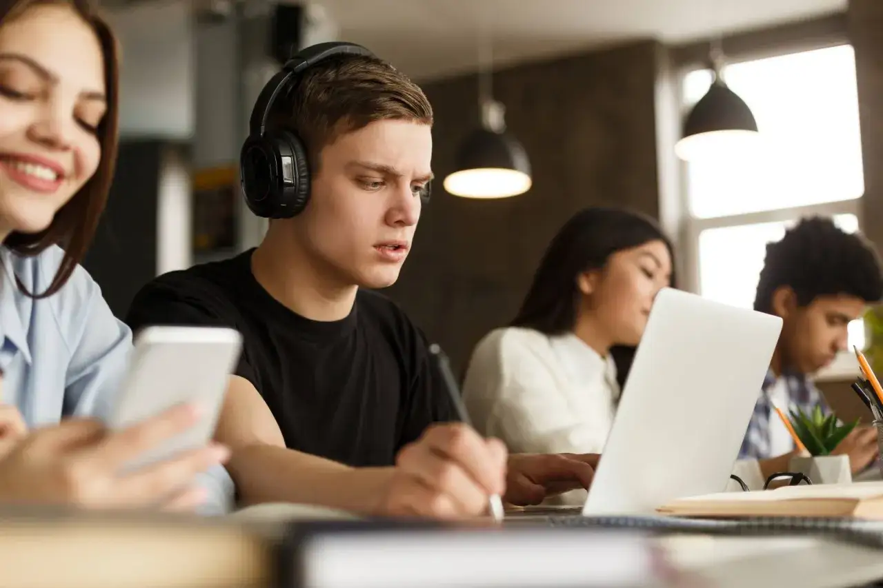 Junge Leute lernen und arbeiten konzentriert an Laptops und Smartphones. Sie studieren Digitalisierung und bereiten sich auf die Zukunft vor.