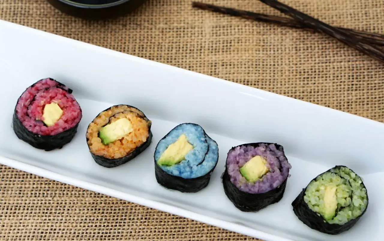Fem f&auml;rgglada bitar vegetarisk sushi med avokado i mitten, serverade p&aring; en vit tallrik.