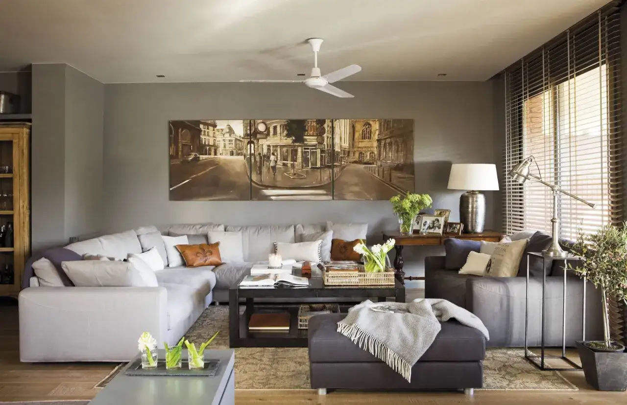 Salones en gris y madera oscura. Sof&aacute; modular gris, mesa de centro oscura, cuadro de paisaje urbano y detalles decorativos.