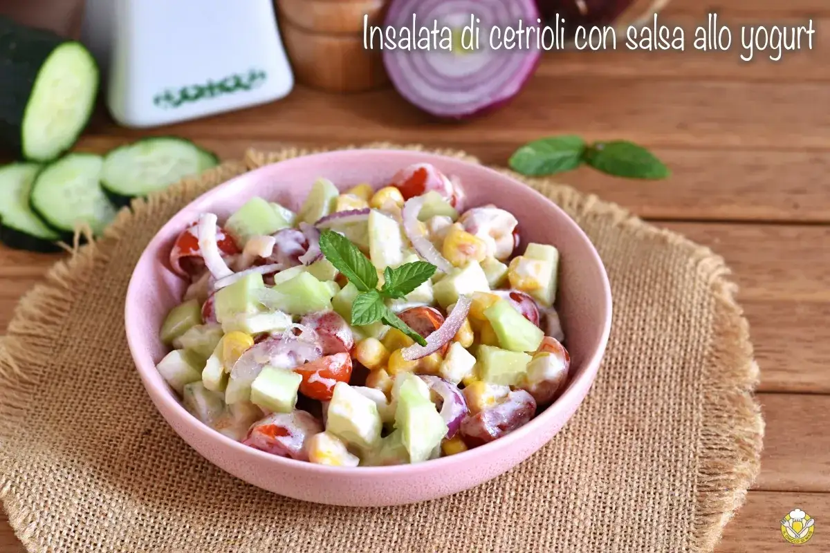 Deliziosa insalata di cetrioli con pomodorini, mais e cipolla rossa, condita con una cremosa salsa allo yogurt.