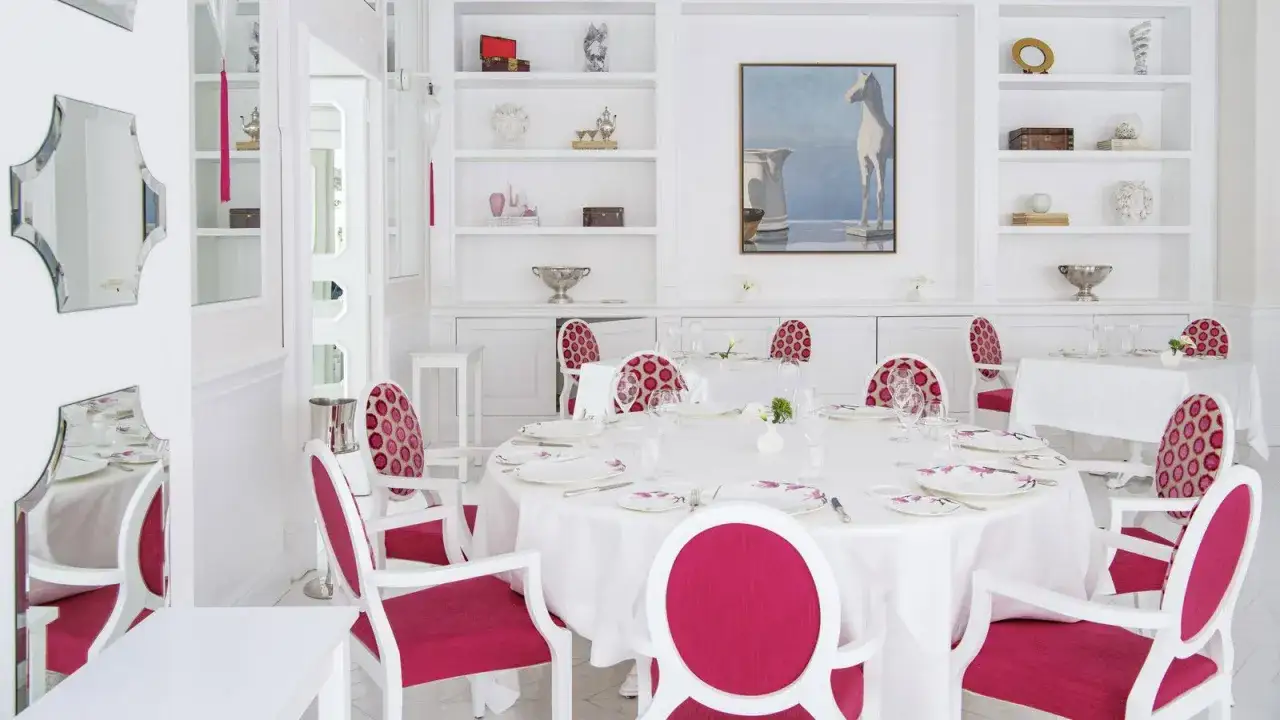 Sala da pranzo elegante con tavoli apparecchiati e sedie fucsia, un ambiente che evoca l'alta cucina di Don Alfonso, stelle Michelin.