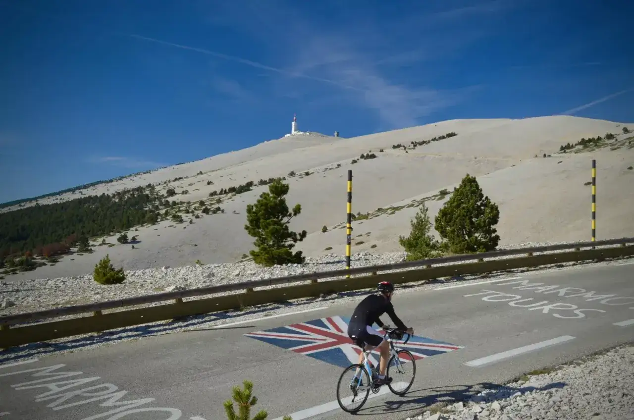 Ciclista affronta la dura salita del Mont Ventoux, con la bandiera britannica dipinta sull'asfalto.