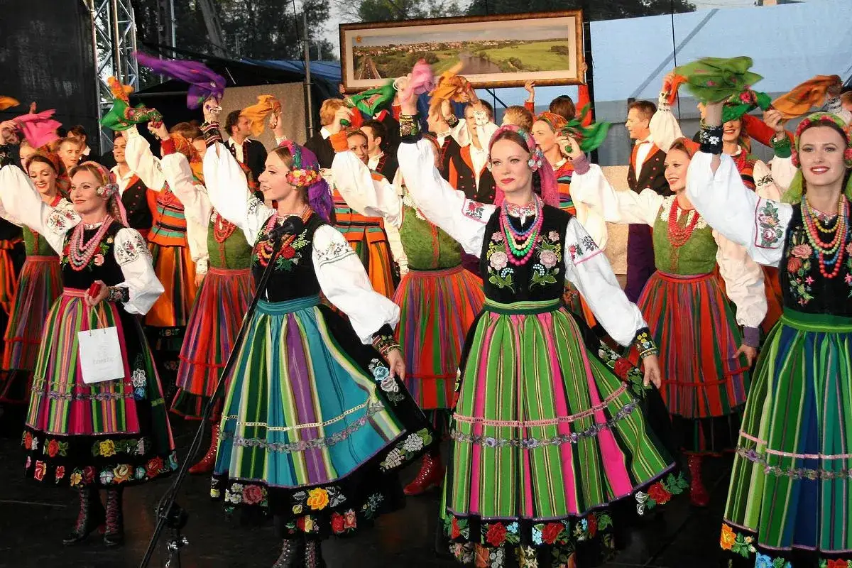 Tancerki w barwnych strojach ludowych, z tamtej strony Wisły tekst na obrazie.