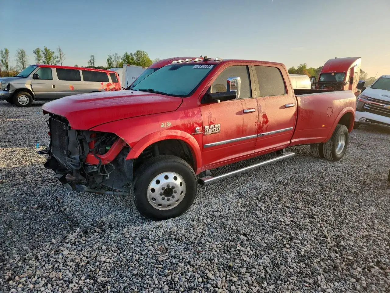 Czerwony Dodge Ram 3500 z podwójnymi tylnymi kołami, uszkodzony z przodu, stoi na żwirowisku.
