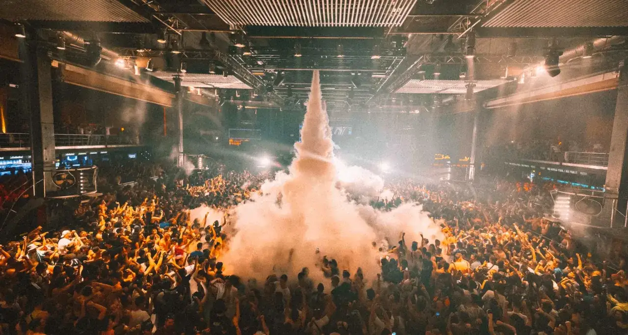 Multitud en una **rave Madrid** disfrutando de un espectáculo de humo y luces.