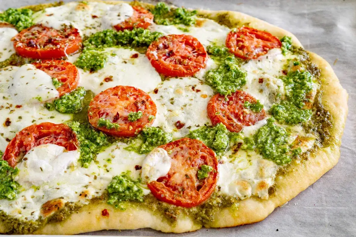 Pizza pesto avec tomates fra&icirc;ches et mozzarella fondue, un d&eacute;lice color&eacute; et savoureux.