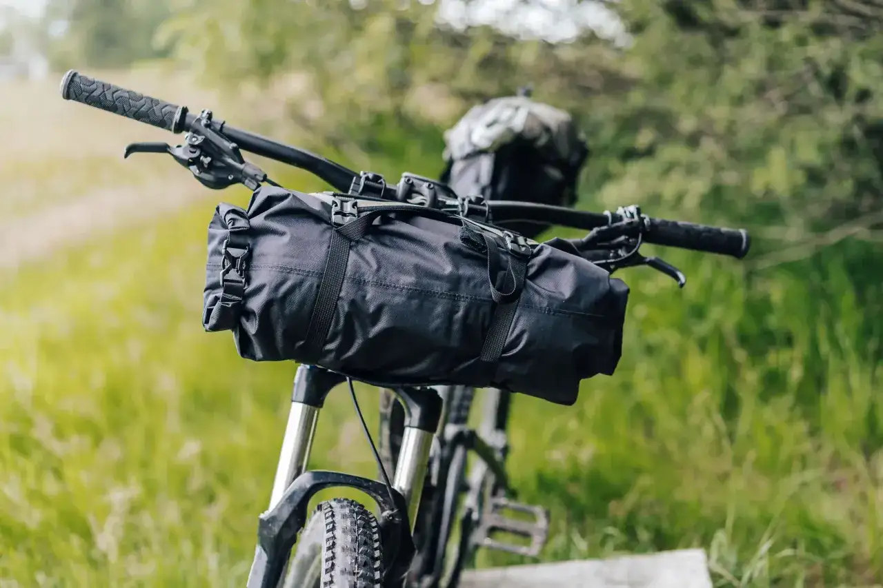 Schwarze Lenkertasche mit Schnallen, bereit für die Bikepacking Packliste. Ein Abenteuer wartet!