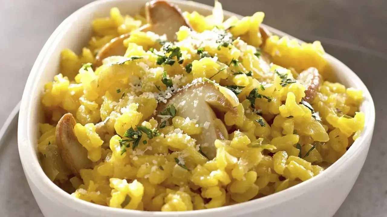 Un cremoso arroz a la milanesa con champiñones y perejil picado, espolvoreado con queso rallado.