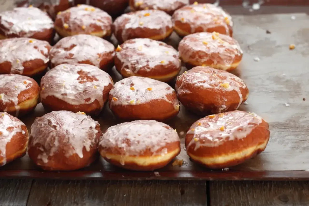 Pączki z lukrem do pączków, posypane skórką pomarańczową, czekają na spróbowanie.