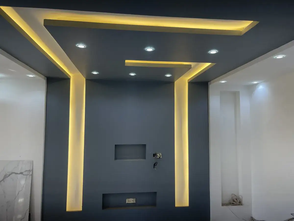 Un **double plafond** moderne avec &eacute;clairage indirect jaune et spots encastr&eacute;s. Lignes g&eacute;om&eacute;triques audacieuses.