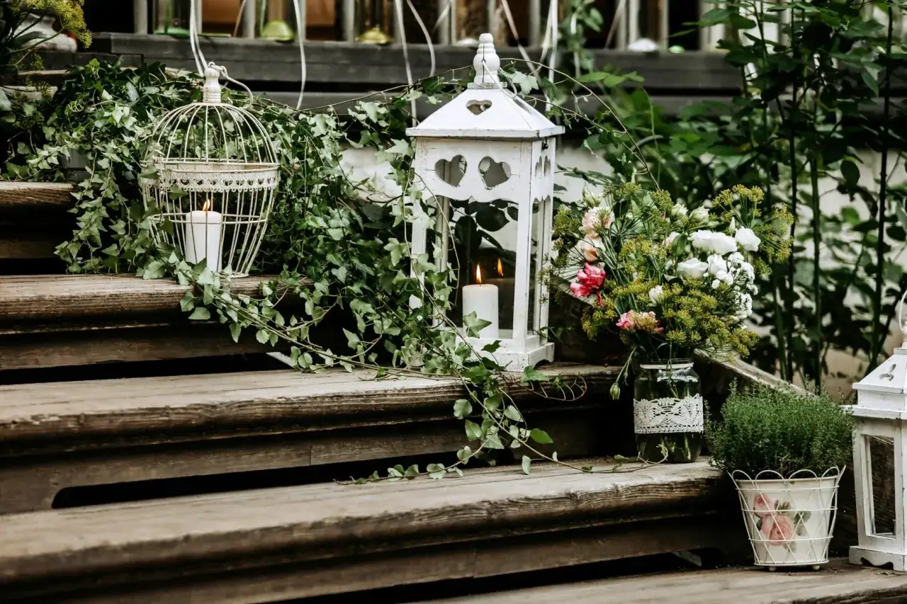 Romantische Dekoration mit Laternen, Kerzen und Blumen, um den hauseingang gestalten. Ranken und Grünzeug umgeben die Treppe.