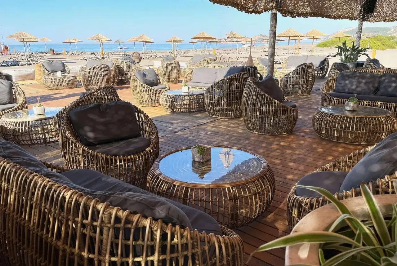 Wygodne fotele i stoliki z rattanu na tarasie przy plaży, idealne na relaks w stylu sarigerme.