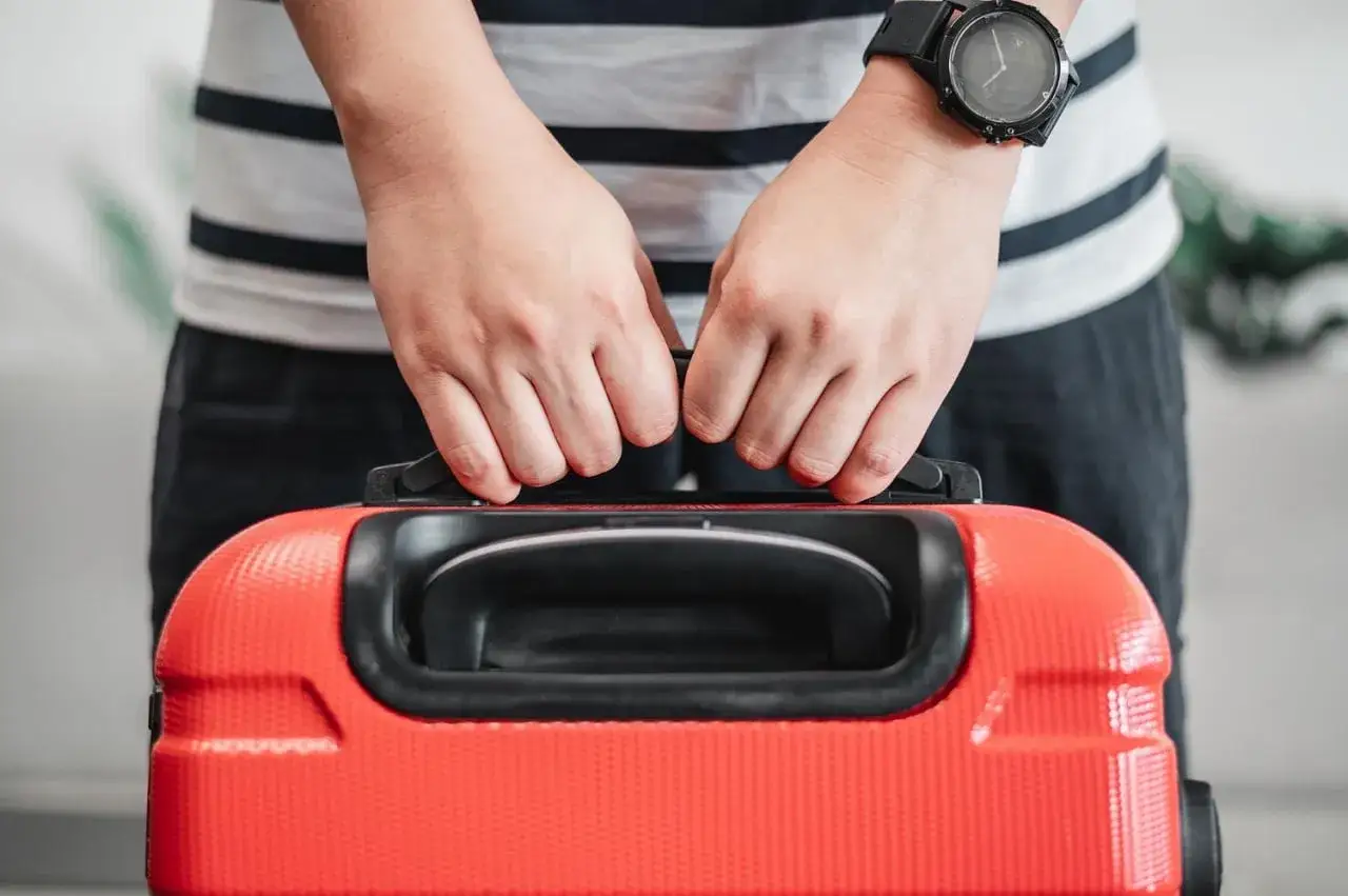 personne pesant une valise avec un pèse-bagage portable