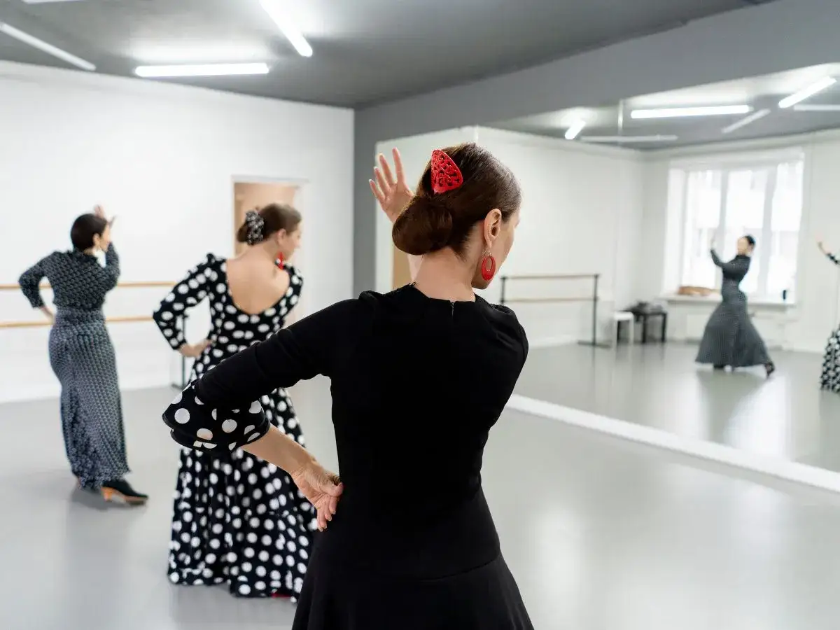Mujeres practican bailar sevillanas con arte en un estudio de danza.