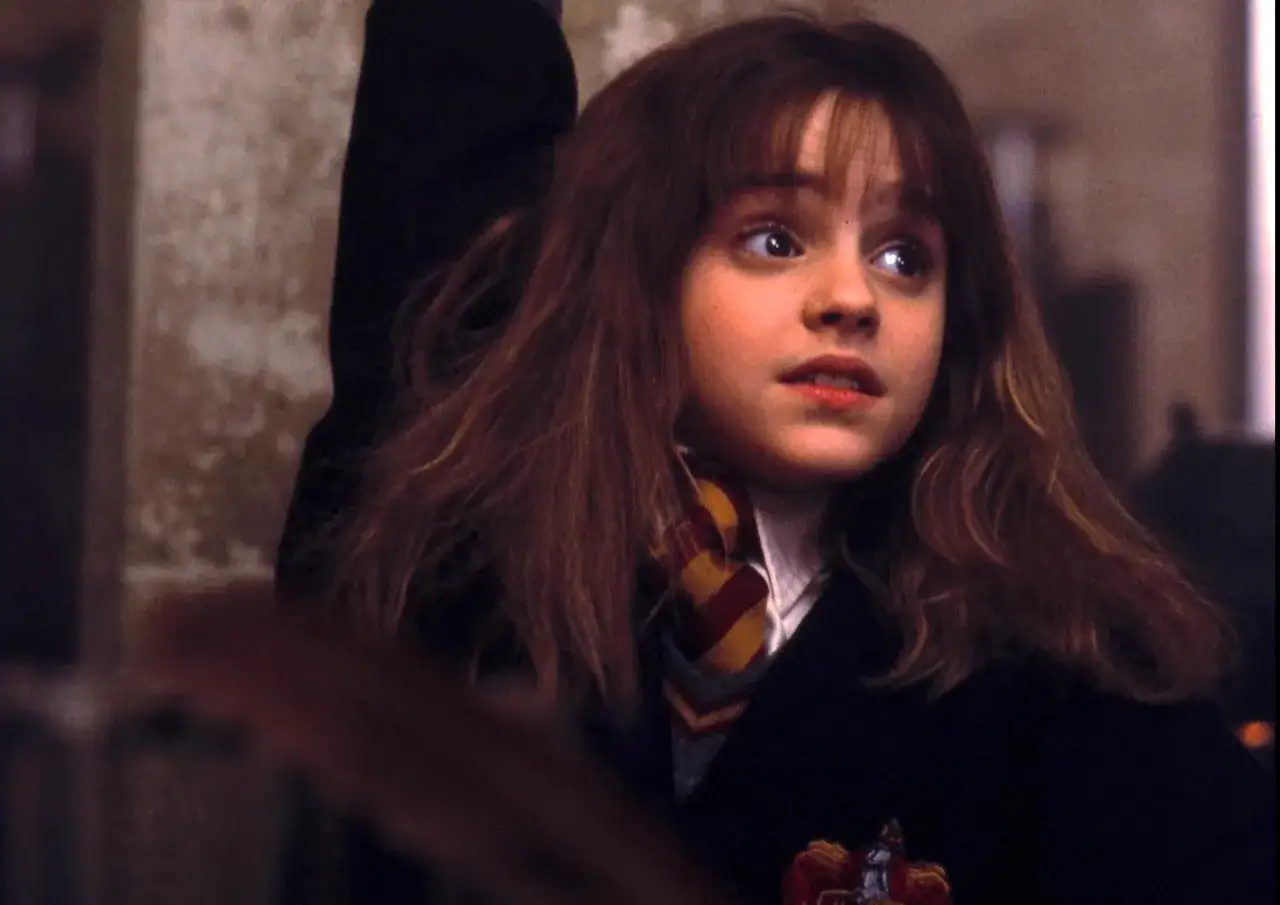 Młoda Hermiona Granger, w którą wcieliła się Emma Watson, z zaciekawieniem spogląda w bok.