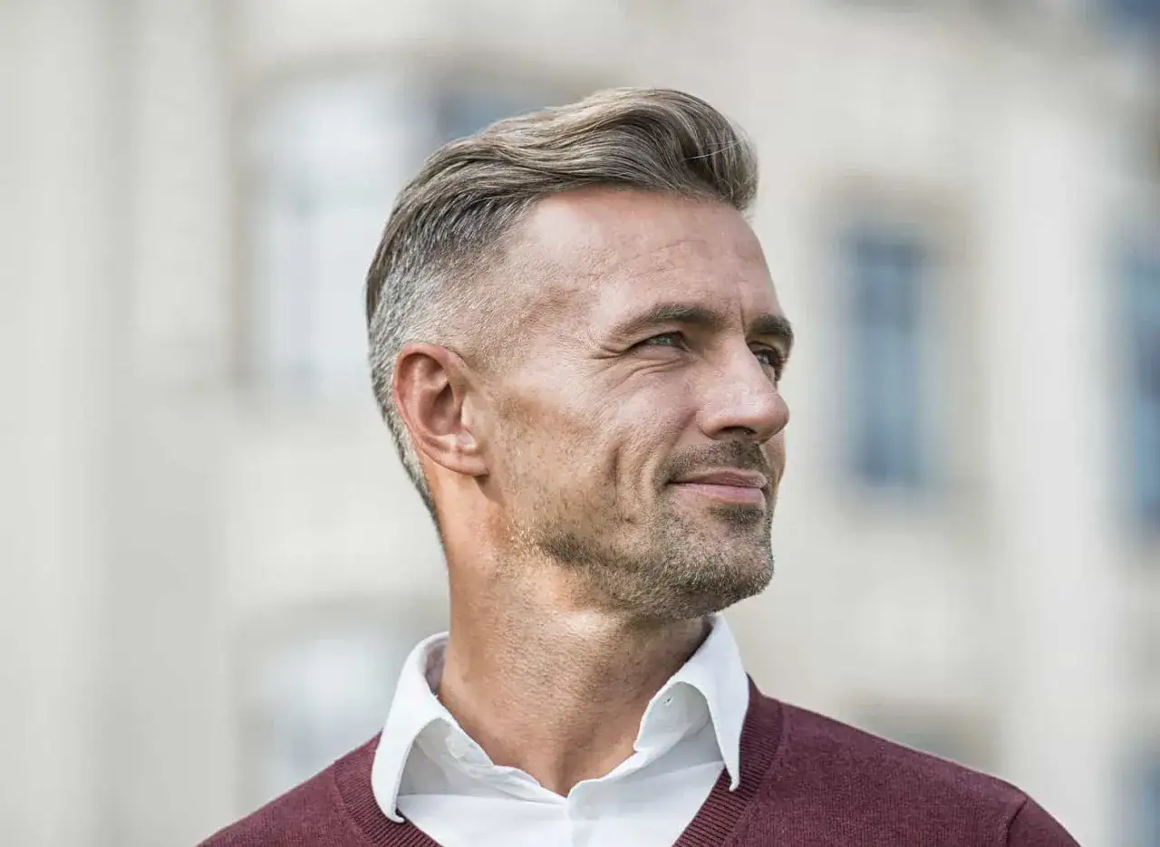 Mann mit grauem Haar, moderner Frisur und leichtem Bart. Seine Geheimratsecken sind kaum sichtbar, ein entspannter Bro-Flow.