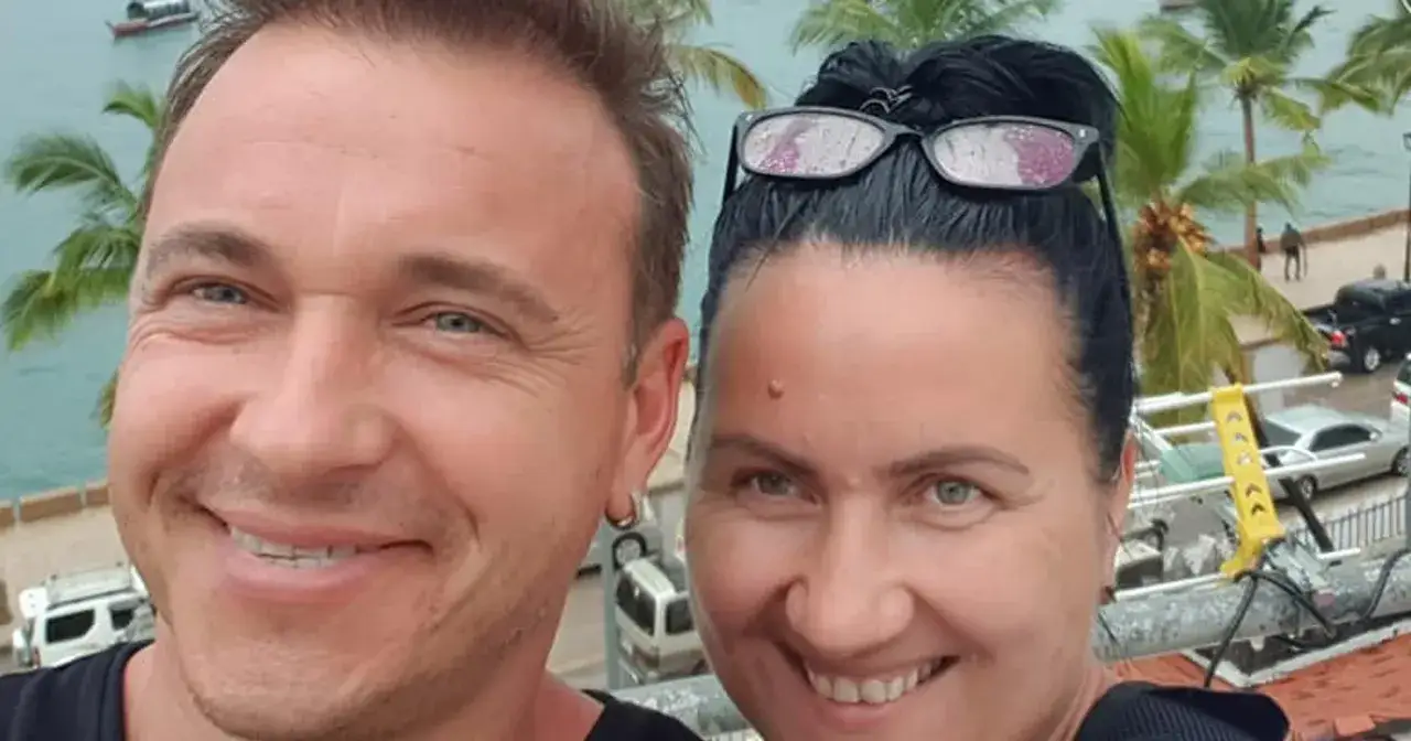 Uśmiechnięta para na tle palmy i morza. Czy Radek Liszewski ma dzieci? Tego nie widać na zdjęciu, ale para wygląda na szczęśliwą.