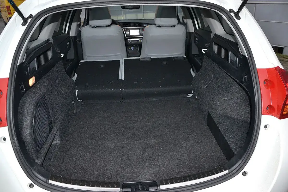 Pusta przestrzeń bagażowa białego kombi Toyota Auris 2006. Siedzenia złożone, gotowe na bagaże.