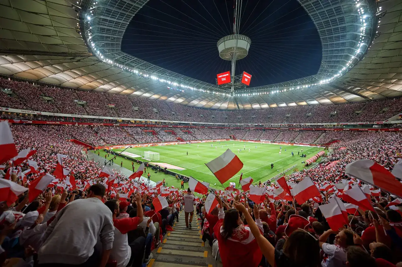 Tysiące kibiców na stadionie, biało-czerwone flagi i emocje towarzyszące meczowi piłka nożna ekstraklasa.