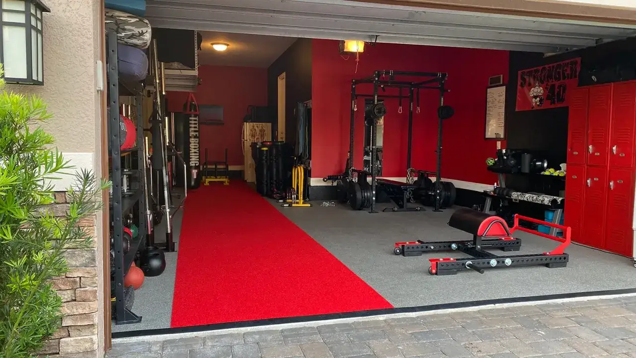 A dedicated garage boxing gym with a red carpet, weight racks, punching bags, and a power cage.