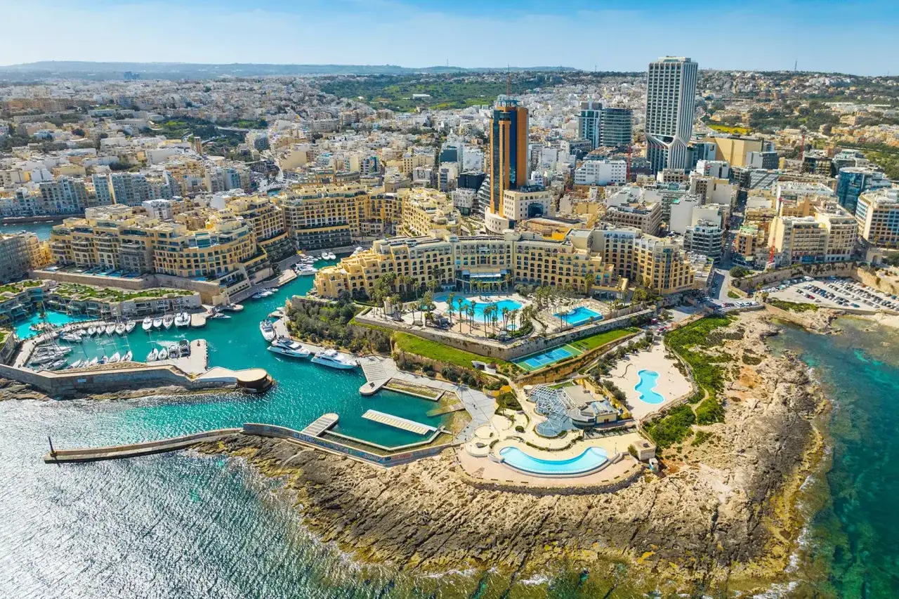 Malta wakacje: luksusowy hotel z basenami i kortami tenisowymi nad turkusową zatoką pełną jachtów.