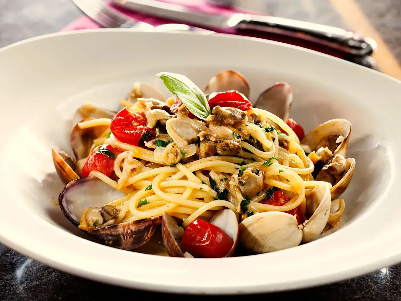 Spaghetti con vongole e pomodorini, un piatto di pasta con pesce fresco e profumato, pronto per essere gustato.