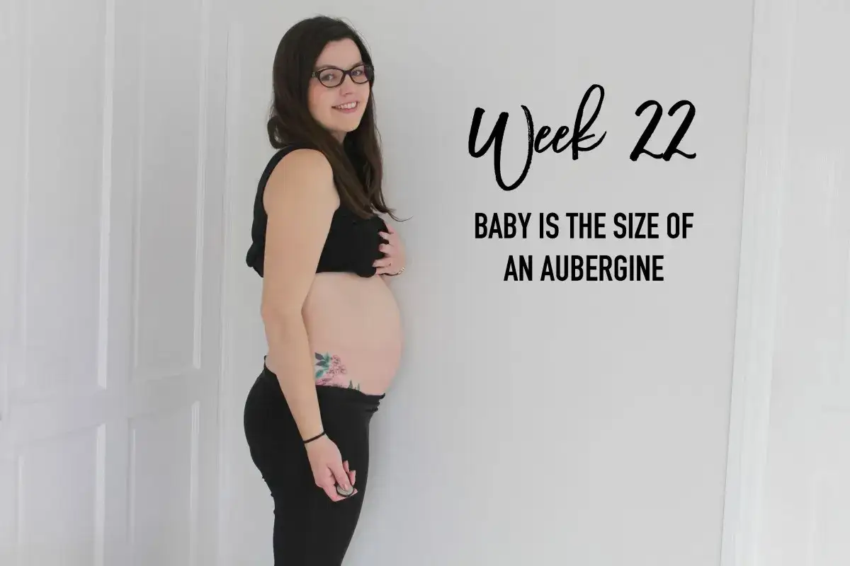 Mujer sonr&iacute;e, mostrando su barriga de 22 semanas. El texto dice 