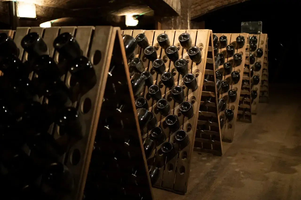 Botellas de cava espagnol en pupitres de madera en una bodega subterránea.