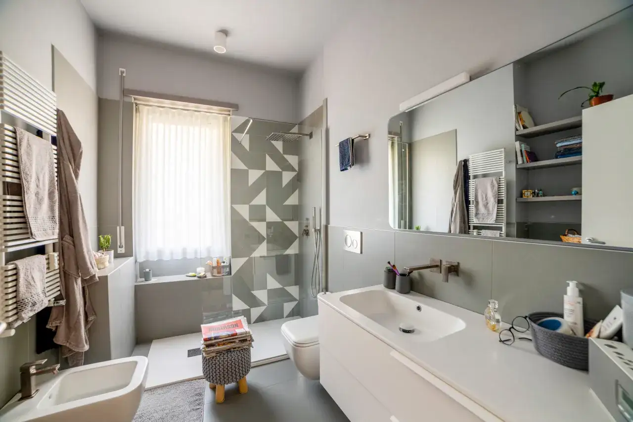 Bagno moderno con doccia su finestra, lavabo, bidet e scaldasalviette.