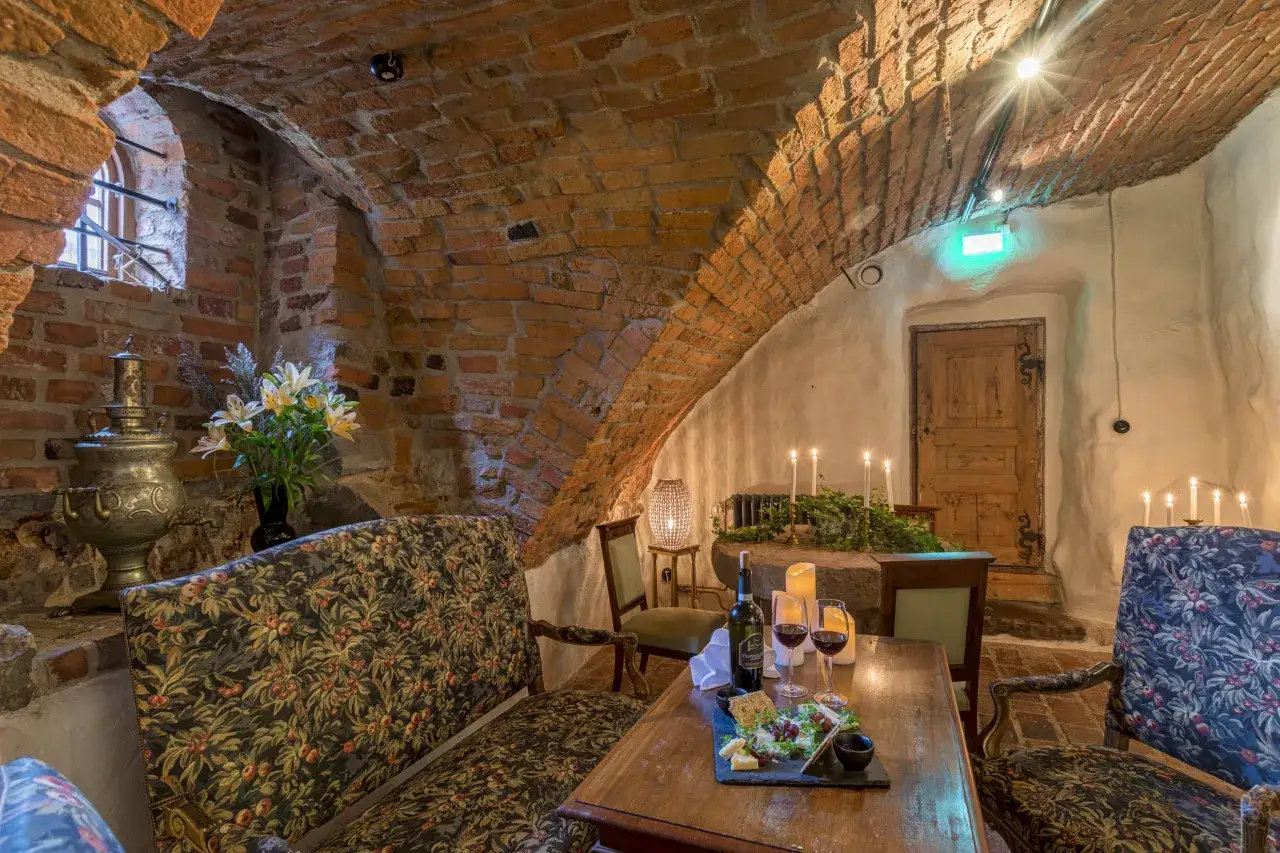 Mysig källare med tegelvalv, samovar, blommor och en ostbricka med vin. En romantisk atmosfär på Mariefreds värdshus.
