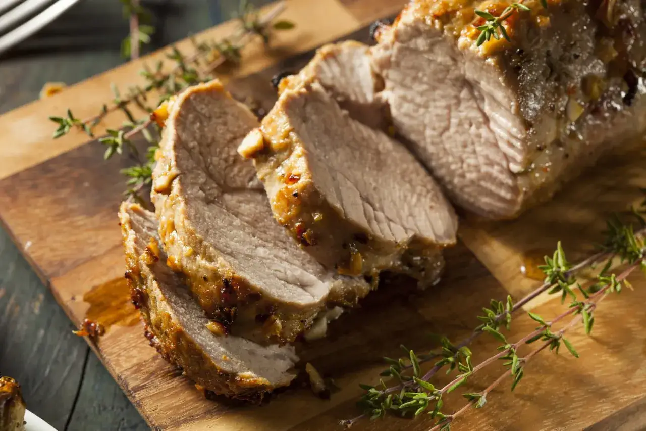 Tranches de filet mignon rôti, juteux et savoureux, garnies de thym frais sur une planche à découper en bois.
