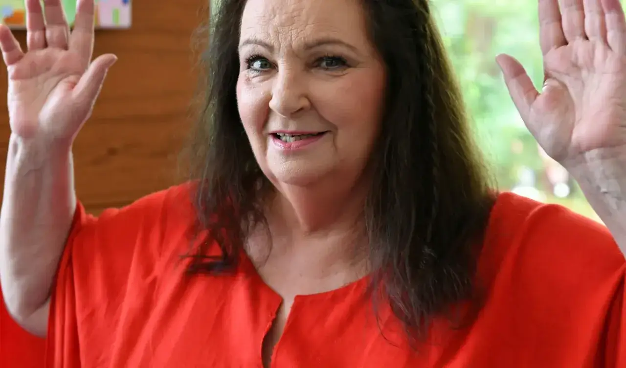 Uśmiechnięta Anna Dymna w czerwonej bluzce, machająca rękami. Wiele wspaniałych anna dymna filmy z jej udziałem.