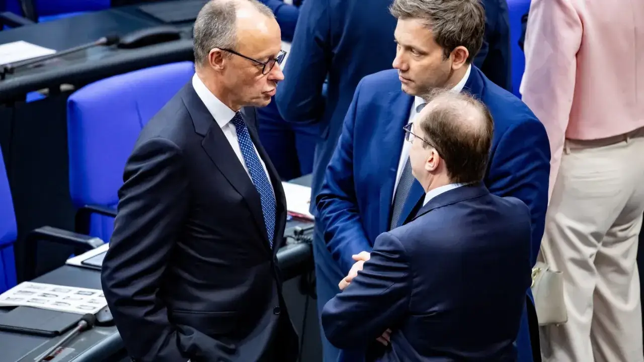 Drei M&auml;nner in Anz&uuml;gen im Bundestag, die &uuml;ber die Deutschland Koalition diskutieren.