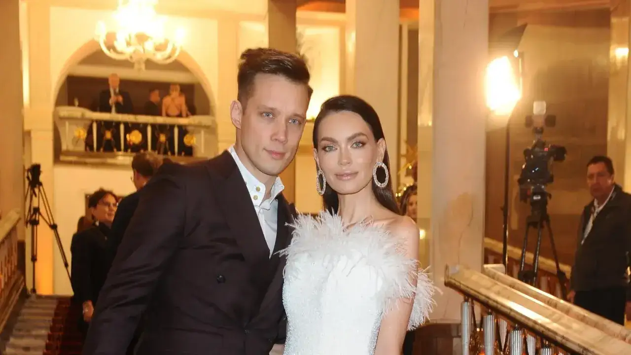 Edyta Zając z partnerem na eleganckim wydarzeniu. Ona w białej sukni z piórami, on w garniturze.