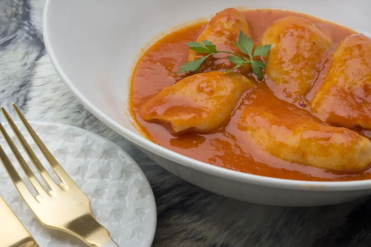 Deliciosos chipirones rellenos de gambas en una salsa de tomate casera, listos para disfrutar con tenedor dorado.