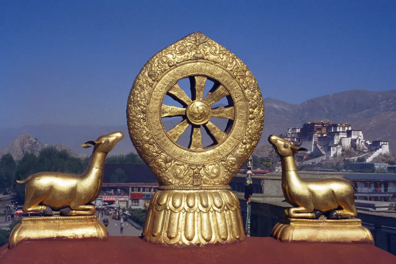 Złote koło Dharmy i dwa jelenie na tle Potala w Lhasie.
