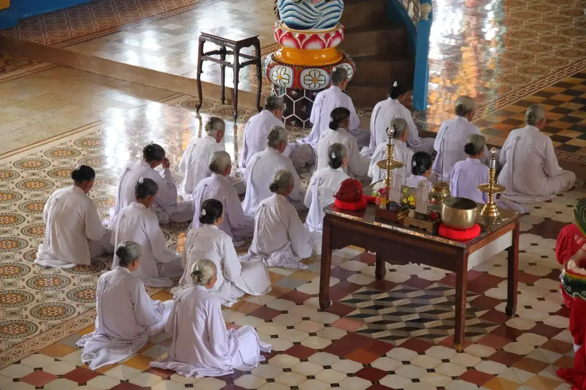 Wietnam religia: mnisi w białych szatach siedzą na podłodze świątyni, pogrążeni w modlitwie.