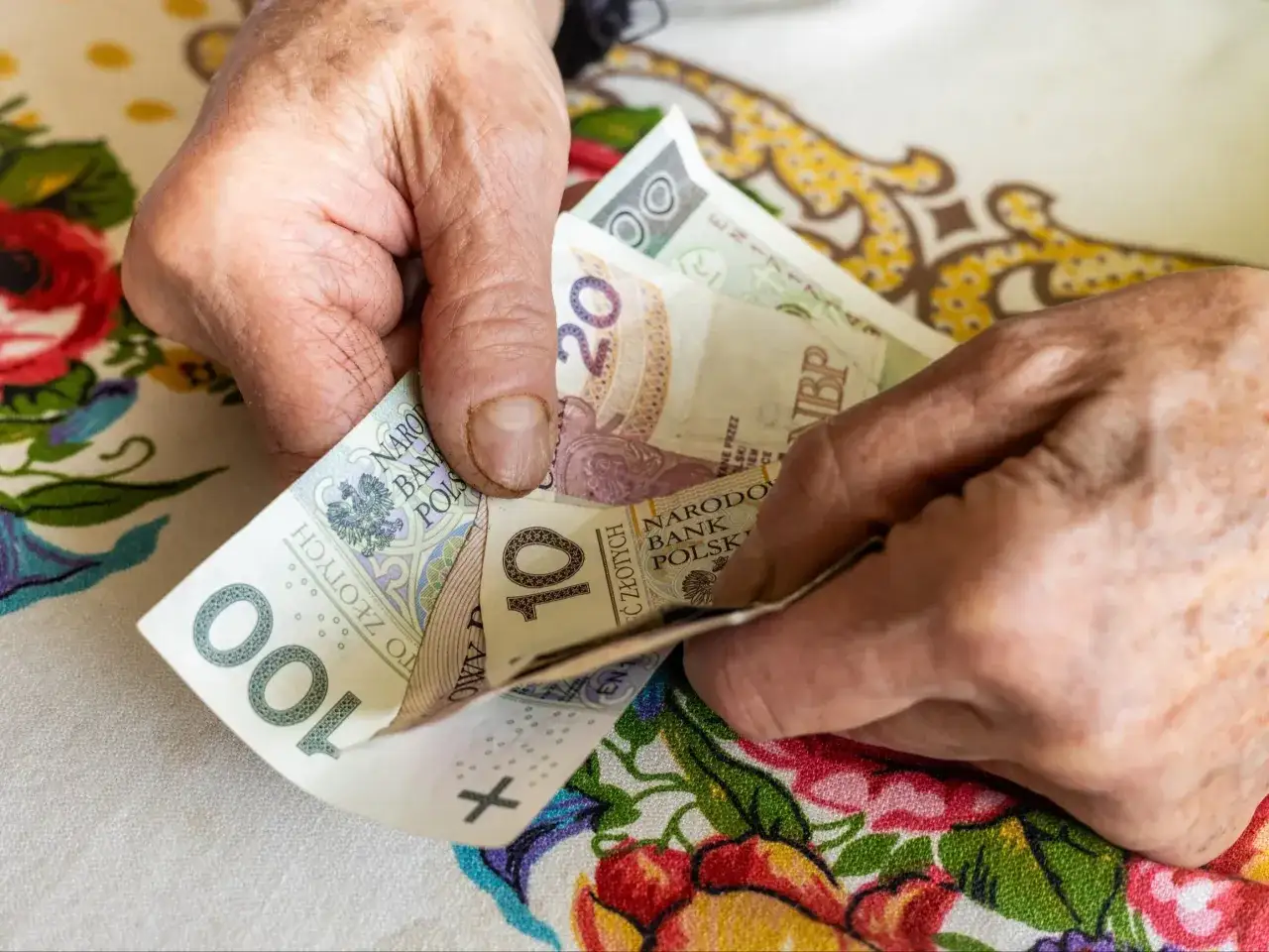 Dłonie liczą banknoty 100 i 20 zł. Czy to już 14 emerytura 2025 netto?