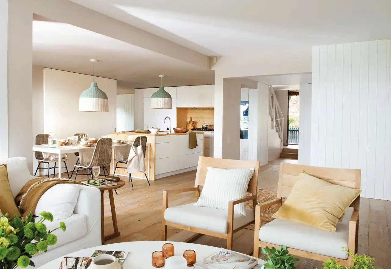 Un **espacio diafano** con sala, comedor y cocina integrados. Muebles de madera clara, textiles neutros y l&aacute;mparas colgantes de mimbre.