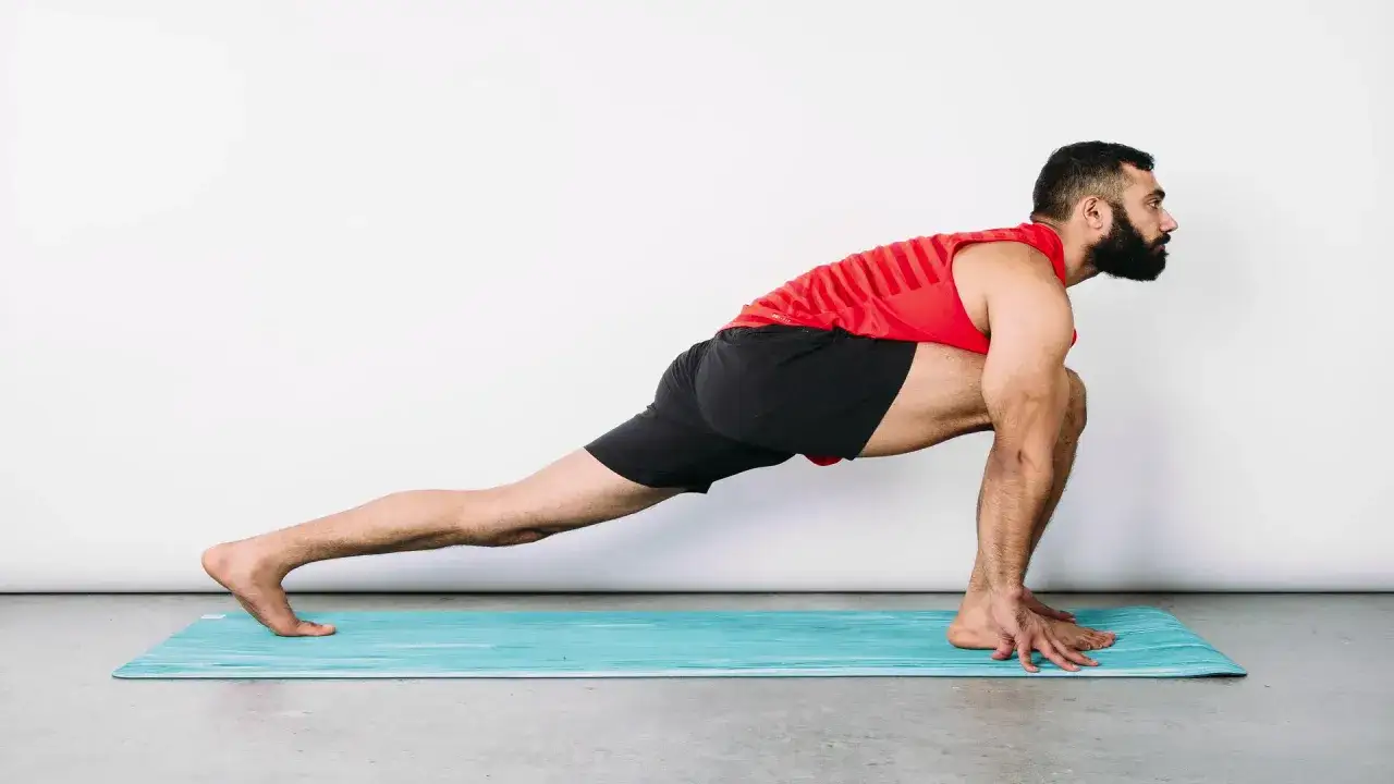 Man in red tank top and black shorts performs a deep lunge, a great bicycle stretch for the hips and legs.