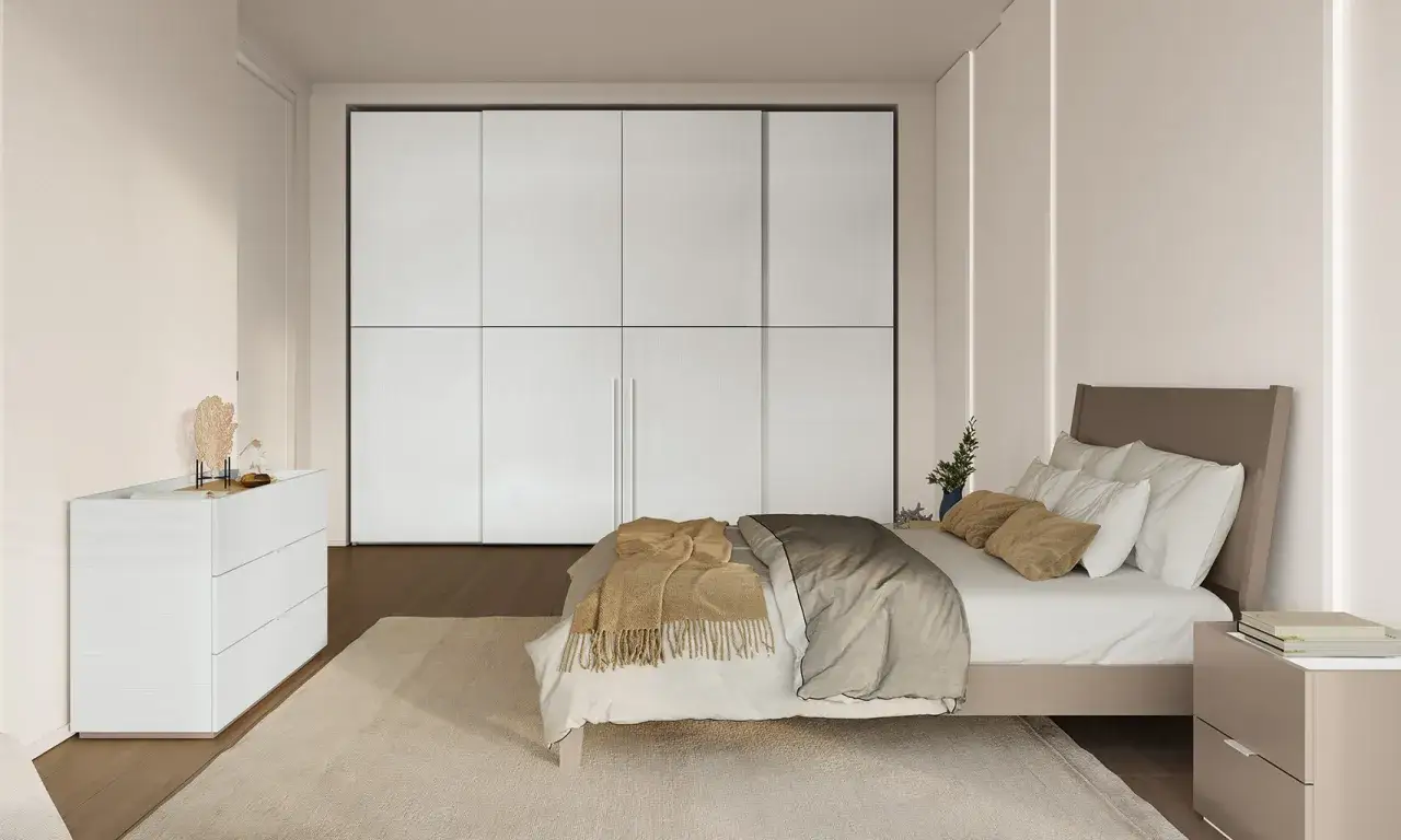 Camera da letto moderna con letto posizionato di fronte a un grande armadio bianco. La posizione letto rispetto alla porta è ideale per un facile accesso.