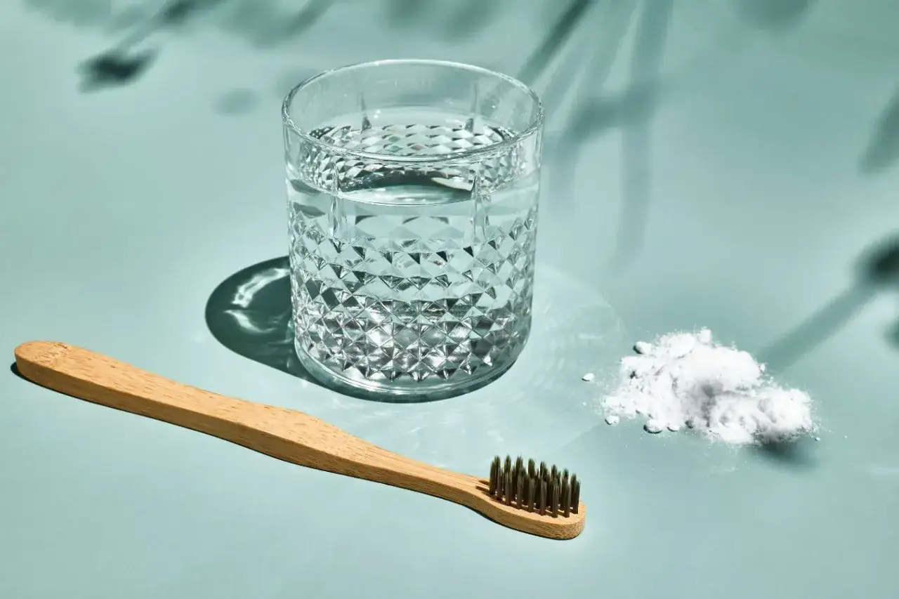 Ein Glas Wasser und eine Zahnbürste liegen neben einem Häufchen weißem Pulver. Bereit für das salzwasser am morgen.