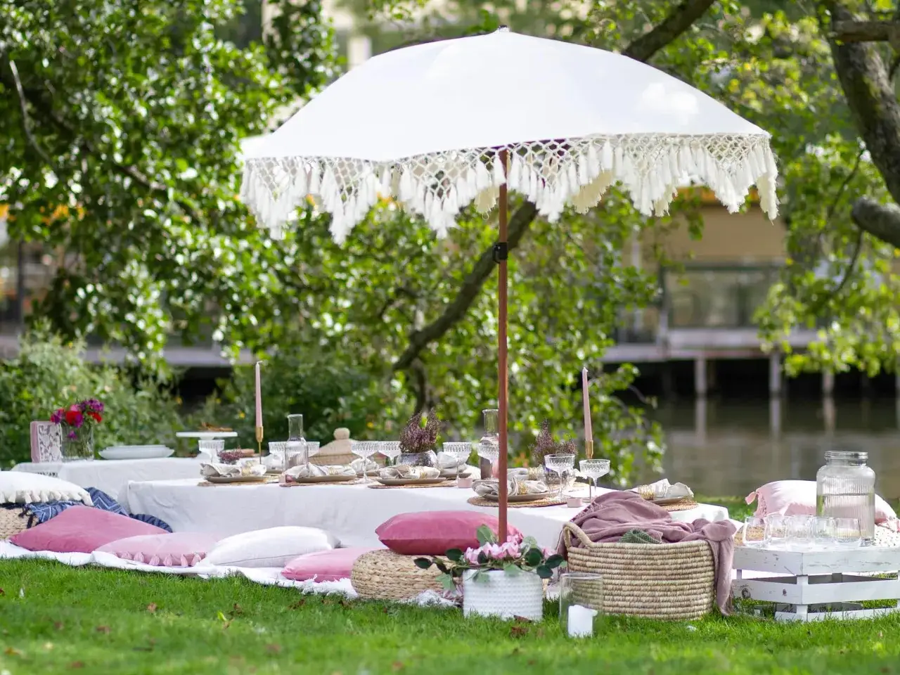 En vacker picknickduk med kuddar och parasoll vid vattnet. Perfekt f&ouml;r en sommar bucket list-dag.